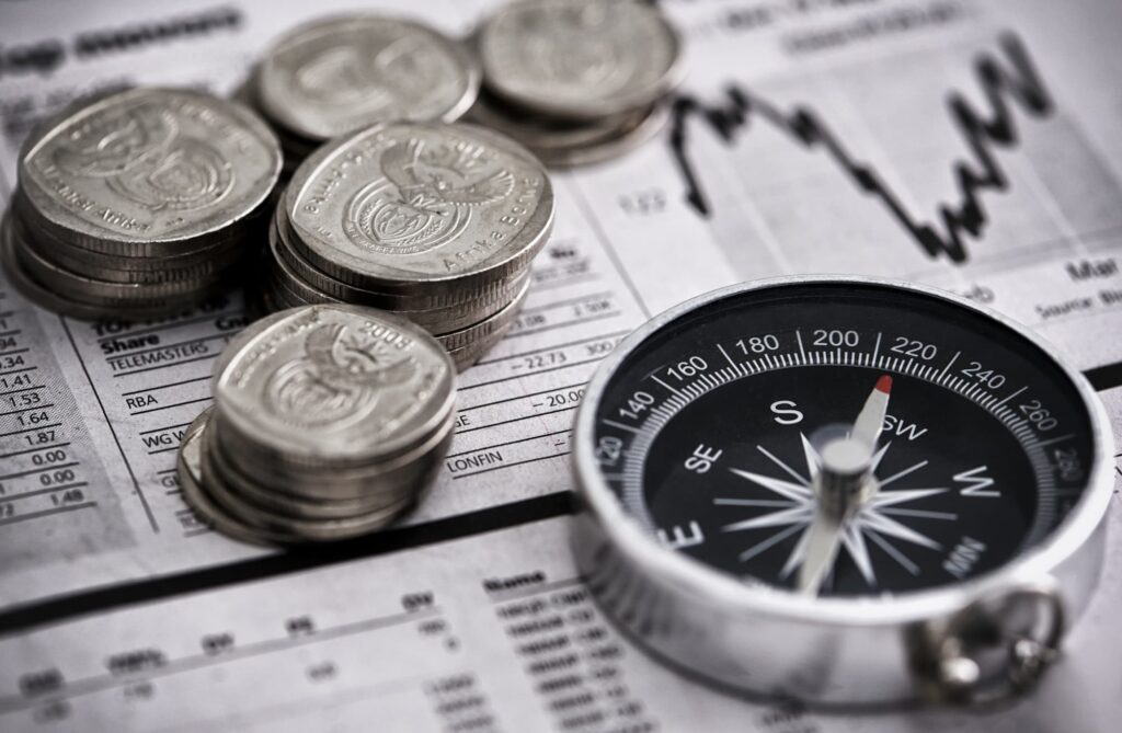 Coins, a compass and a financial newspaper chart